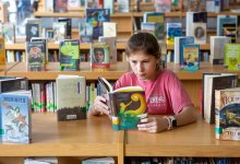 Elementary aged girl reading book in school library