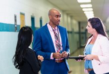 School principal talking to teachers in a school hallway